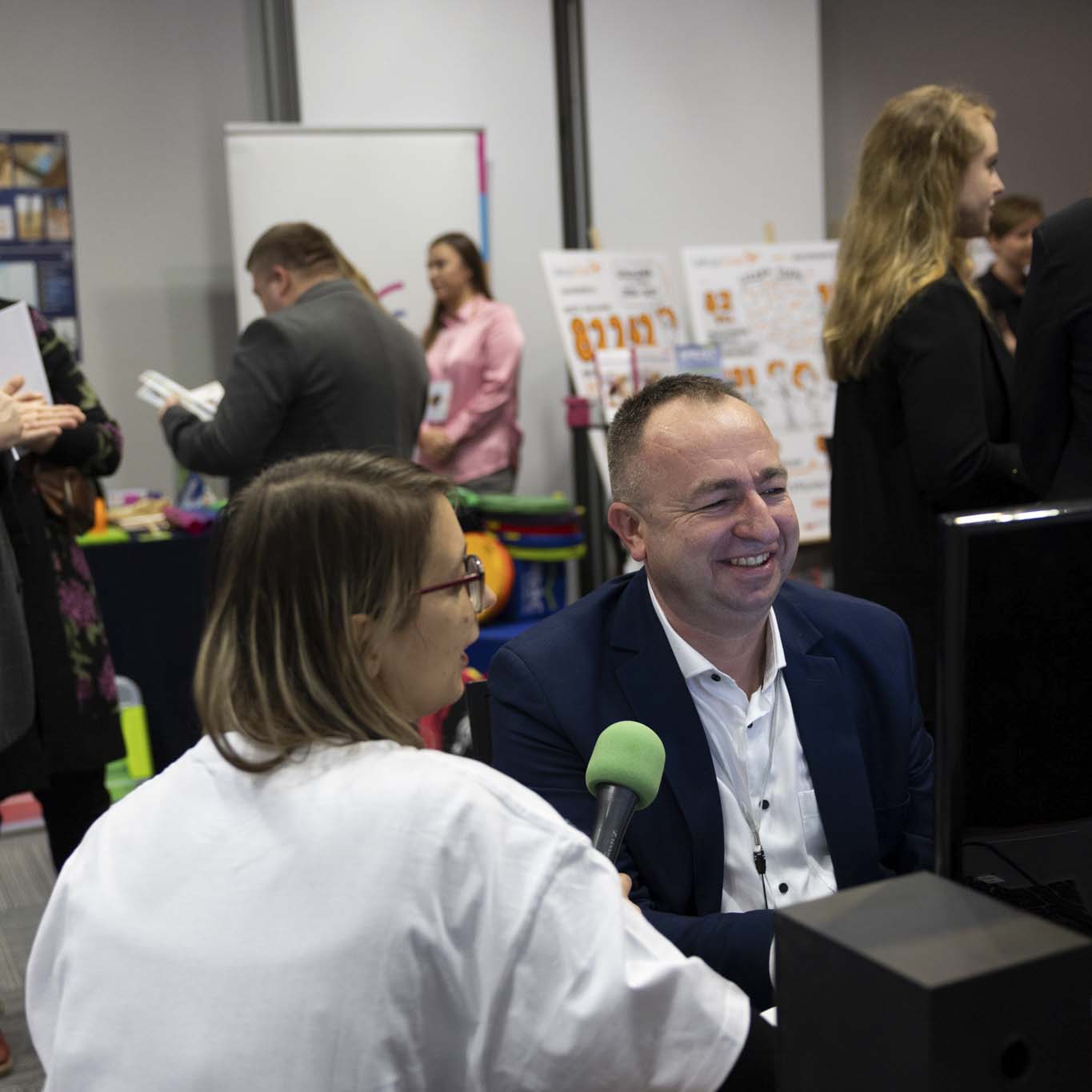 Mężczyzna udziela wywiadu dziennikarce z mikrofonem. W tle pozostali uczestnicy konferencji.