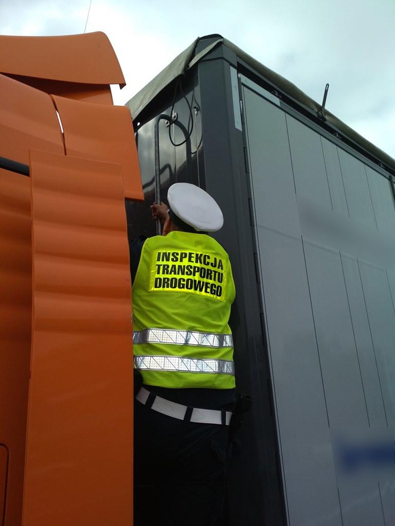 Inspektor wchodzi po drabince na naczepę