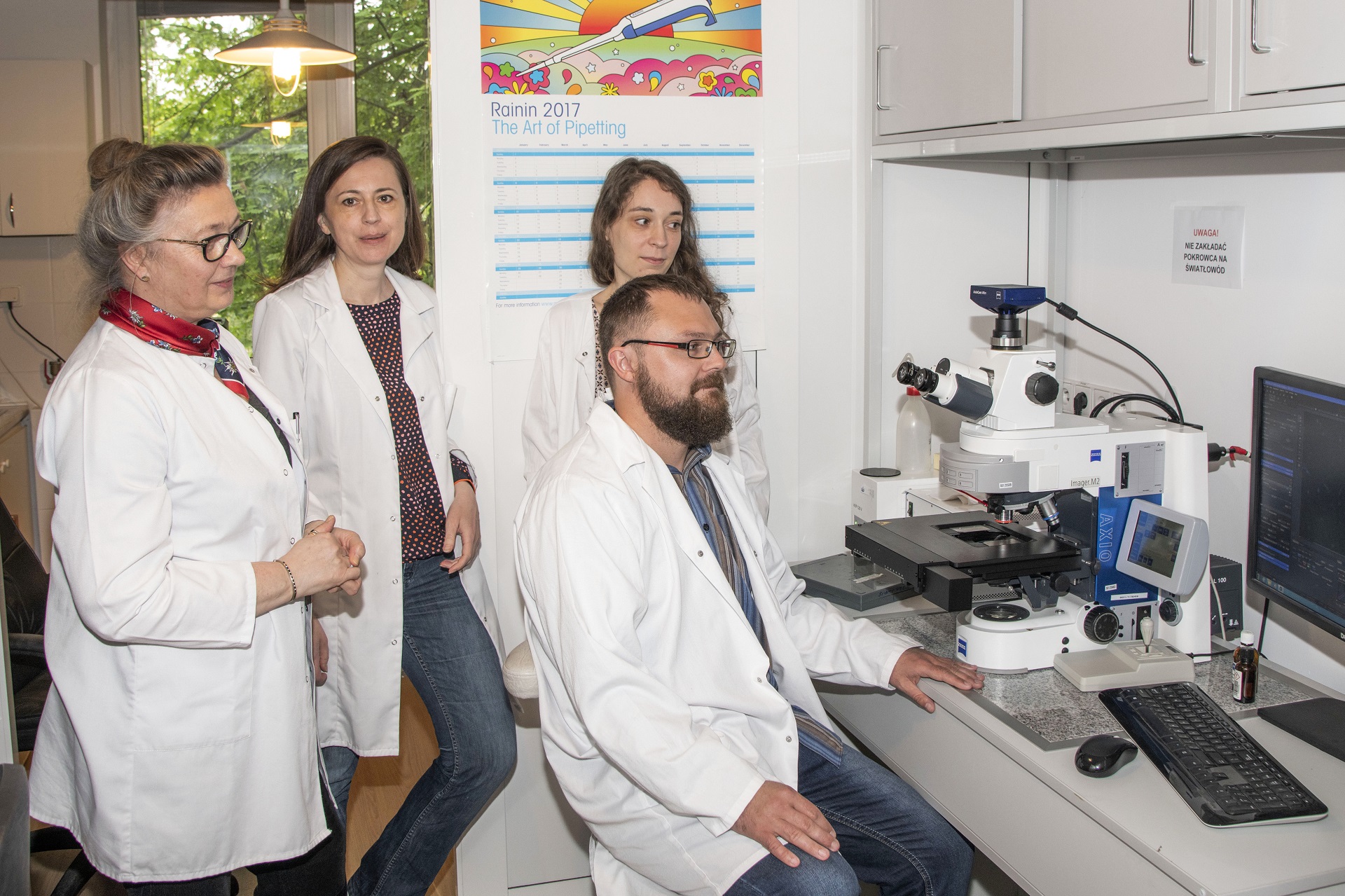 Professor Urszula Sławińska with a team of three, in white coats, while working in the laboratory