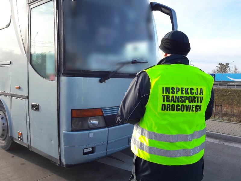 Inspektor ITD stoi przed kontrolowanym autobusem