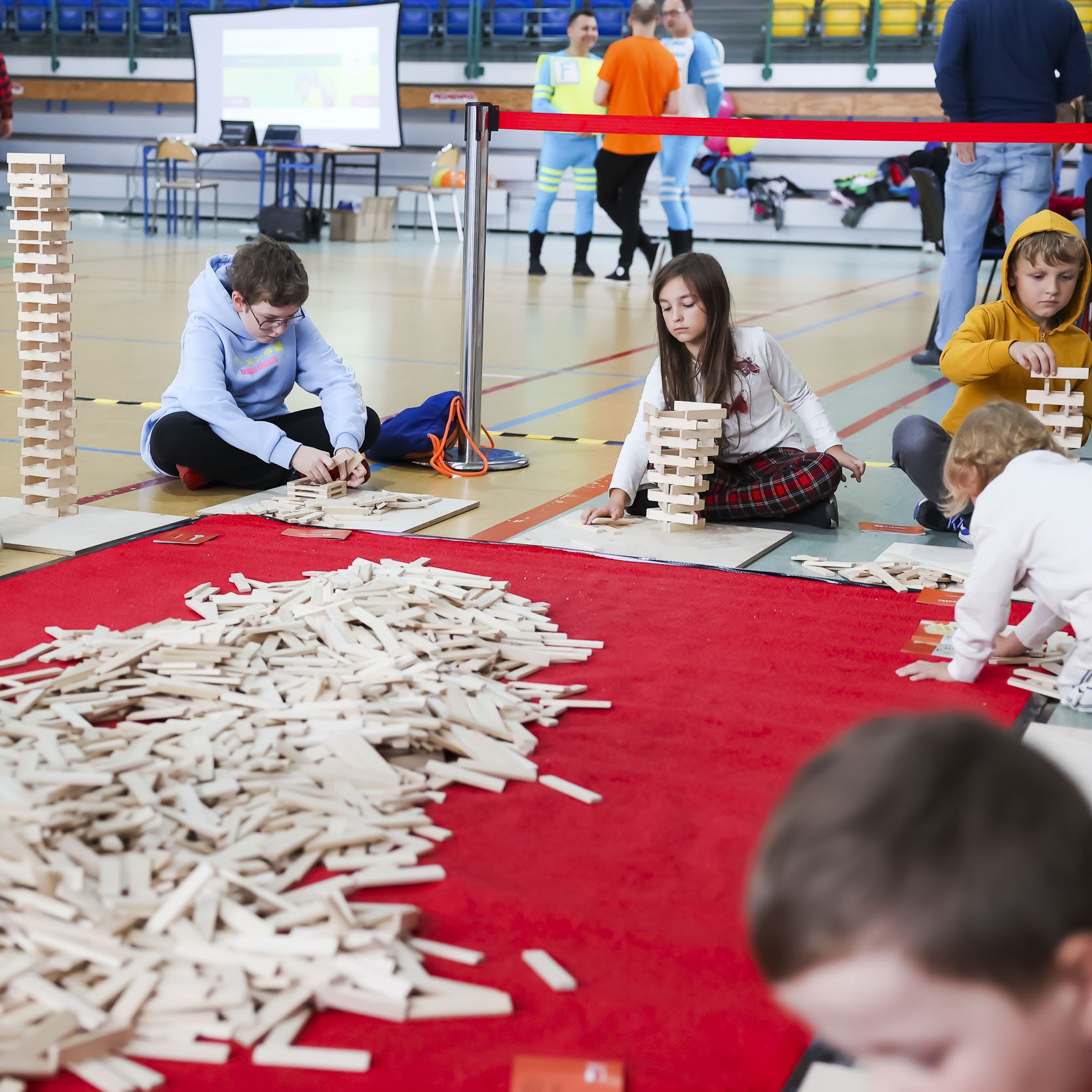 Dzieci siedzące na podłodze układające wieże z drewnianych klocków