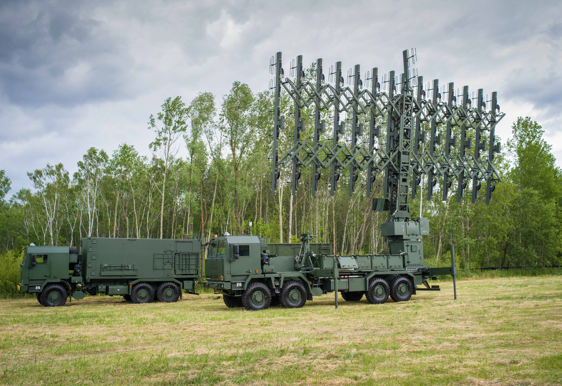 Prototyp Radaru P18PL. Na trawniku stoją zaparkowane wozy bojowe z zamontowanym radarem. W tle las.