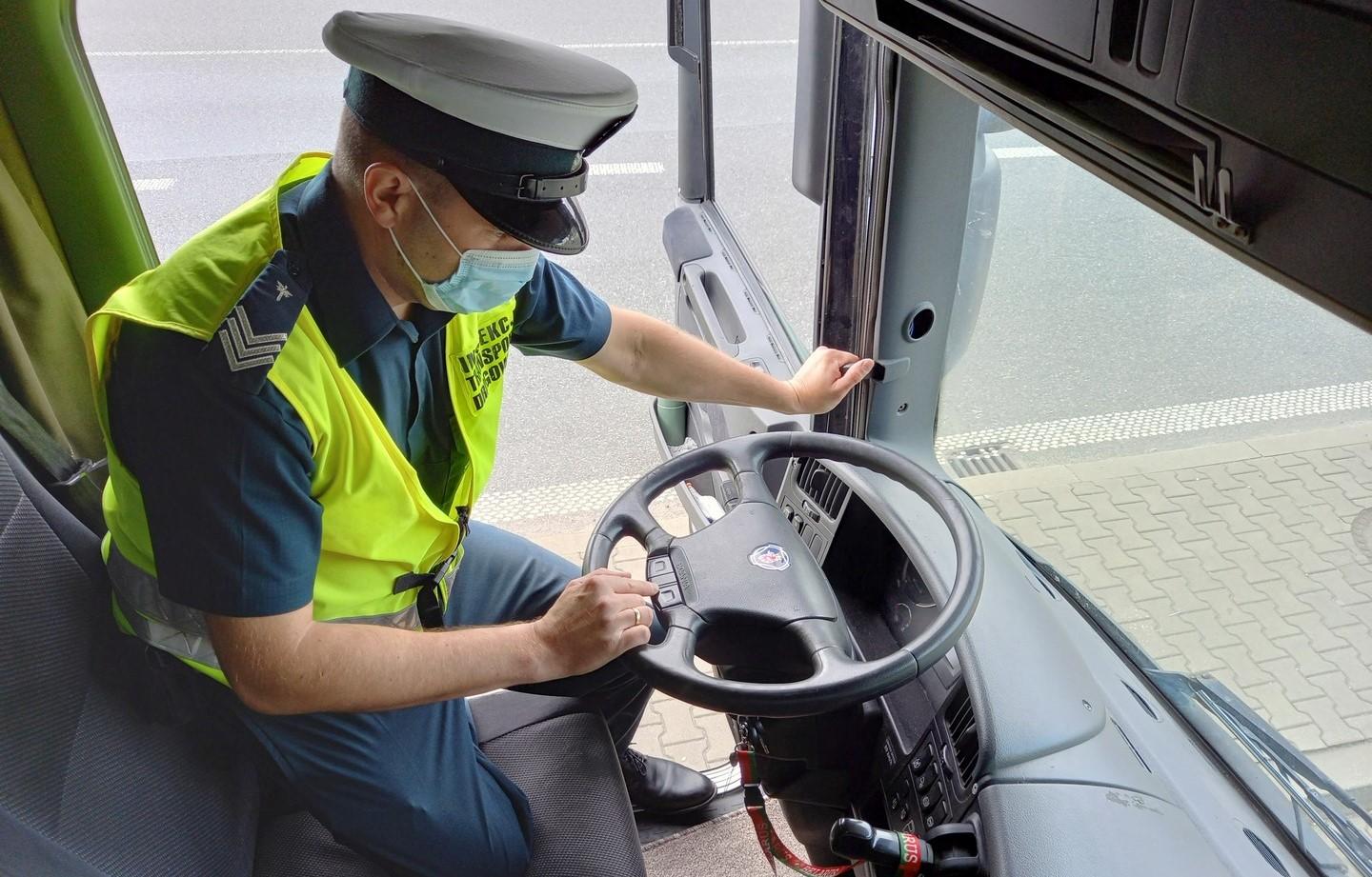 Inspektor znajduje się w kabinie samochodu ciężarowego i sprawdza komunikaty wyświetlane przez komputer pokładowy pojazdu. 