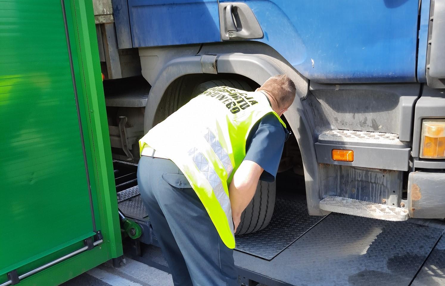 Inspektor kontroluje stan techniczny samochodu ciężarowego na mobilnej stacji diagnostycznej ITD.