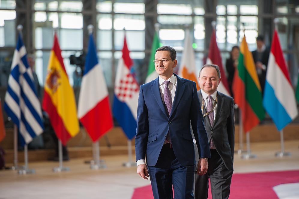 Premier Mateusz Morawiecki i minister Konrad Szymański na czerwonym dywanie w budynku Europa.