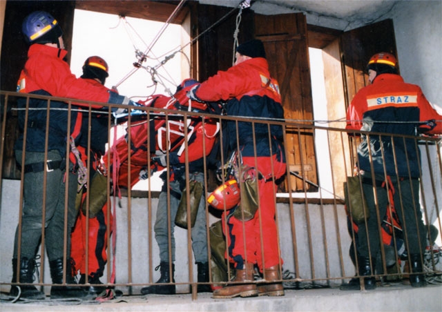Ćwiczenia pięciu strażaków w kombinezonach koloru czerwonego w zakresie ratownictwa wysokościowego wewnątrz obiektu wspinalni przy ulicy Grybowskiej w Nowym Sączu.