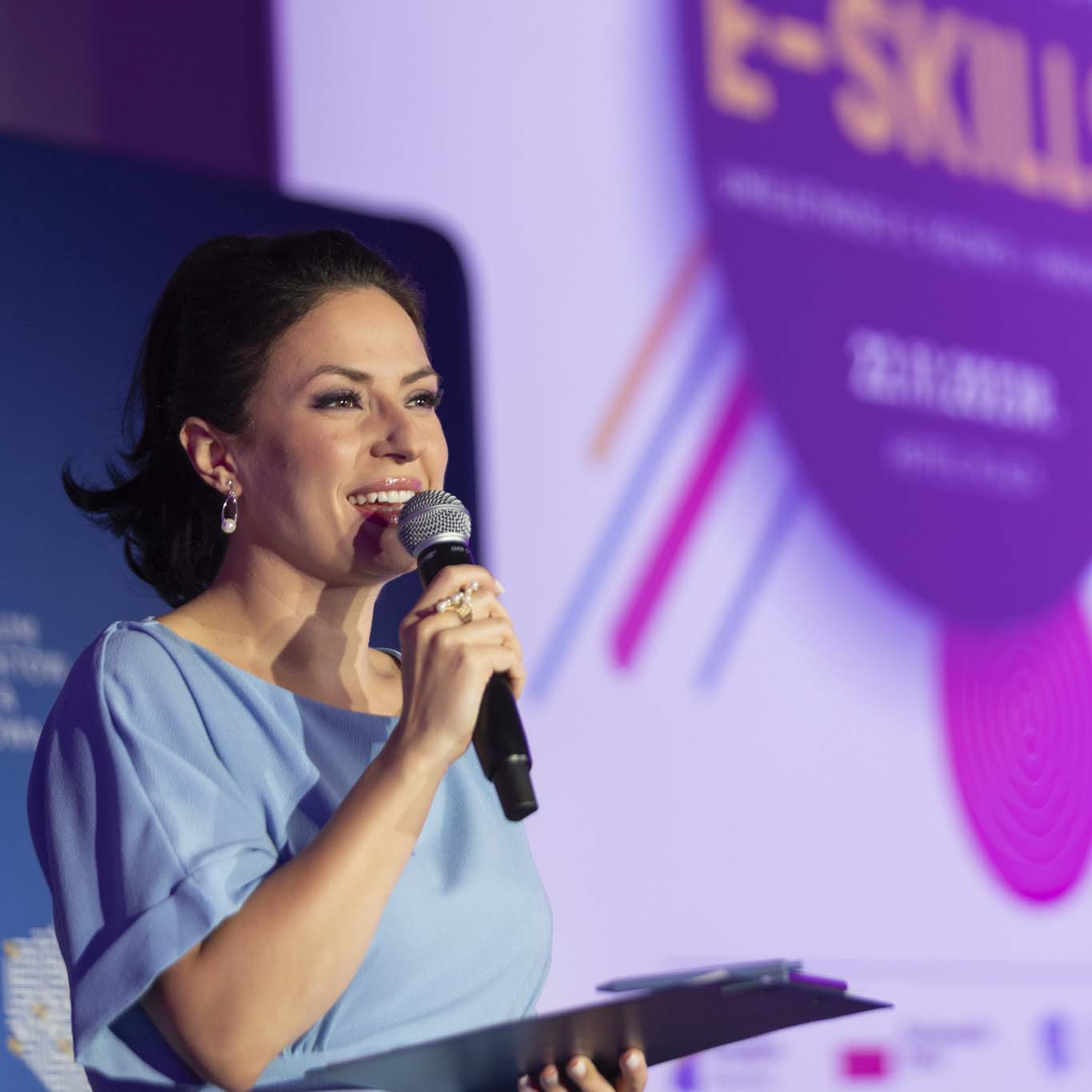 Pani Anna Butrym stoi na podeście i mówi do mikrofonu.