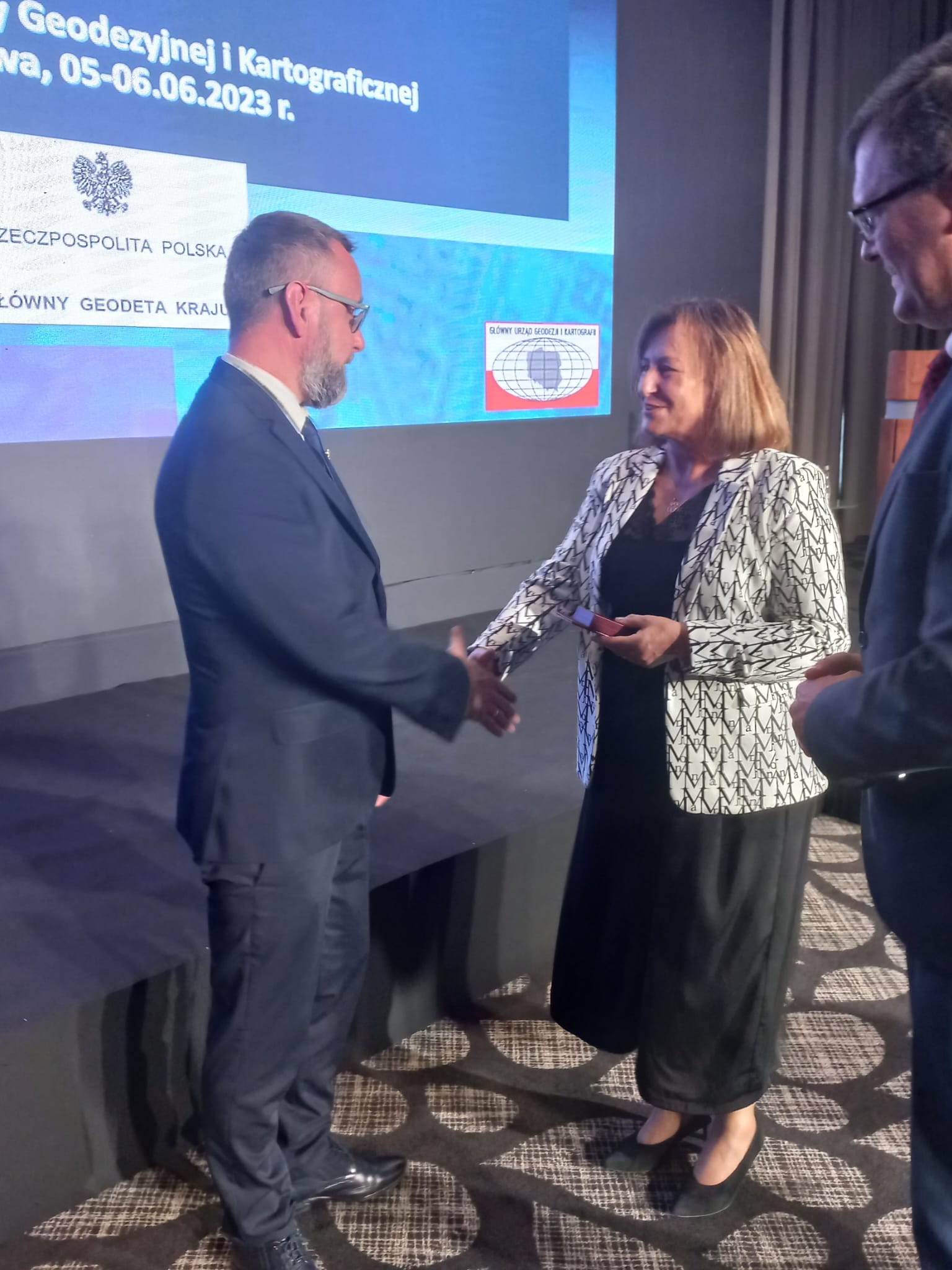 Zdjęcie przedstawia p.o. GGK Alicję Kulkę i Wiceministra Rozwoju Technologii Piotra Uścińskiego wręczających odznaczenie Kamilowi Kowalczykowi