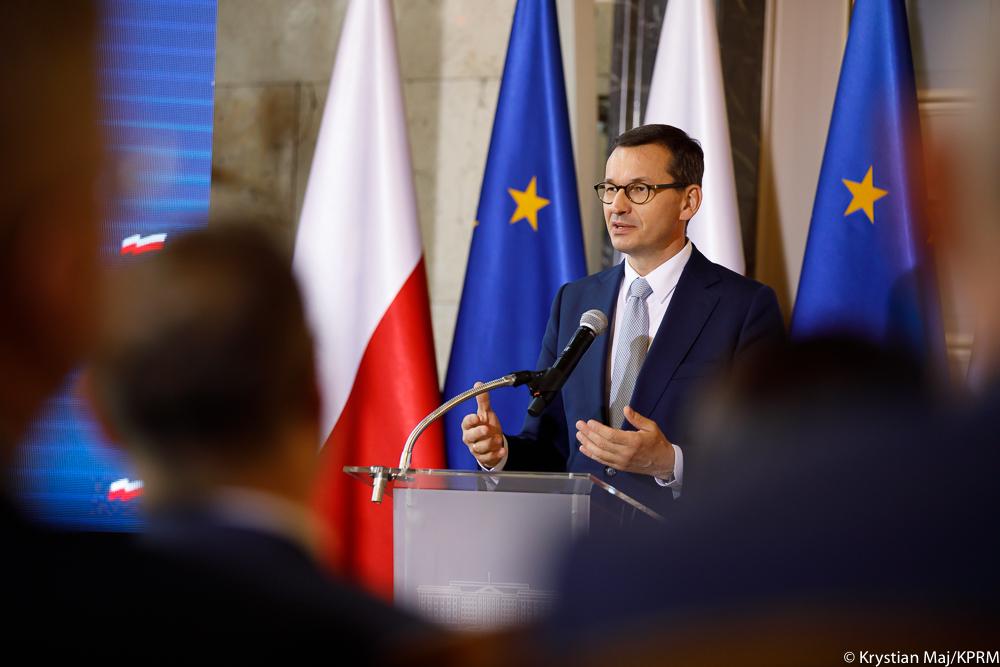 Premier zza przedsiębiorców, na tle flag.