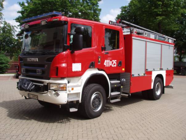 Zdjęcie przedstawia ciężki samochód gaśniczy na podwoziu SCANIA stojący na placu strażnicy.