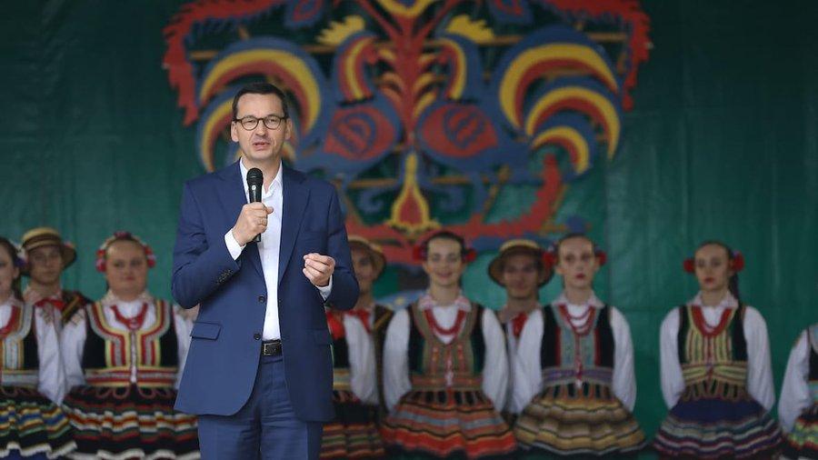 Premier Mateusz Morawiecki stoi podczas przemówienia.