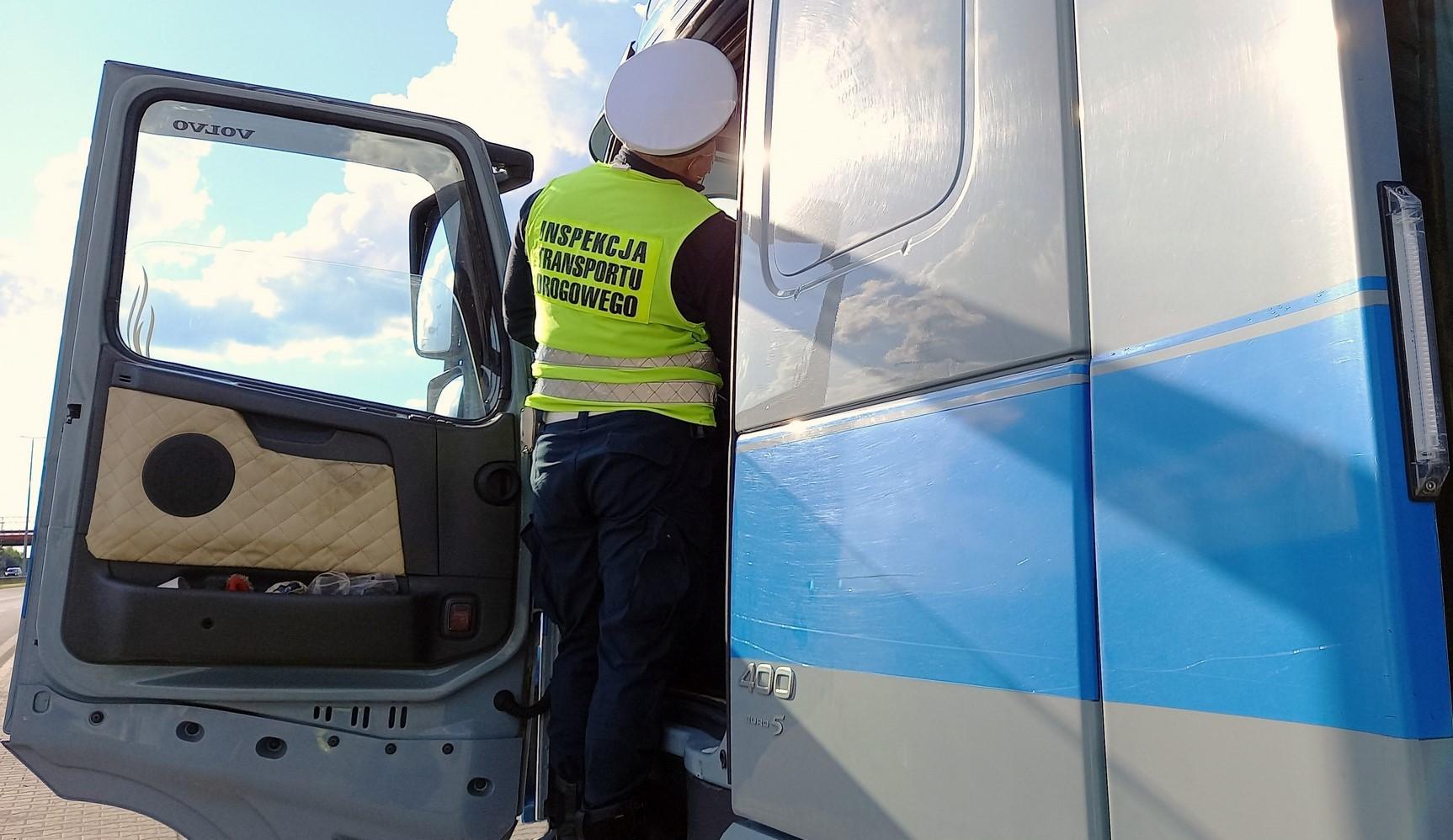 Inspektor ITD stoi na stopniach wejściowych do kabiny ciężarówki.