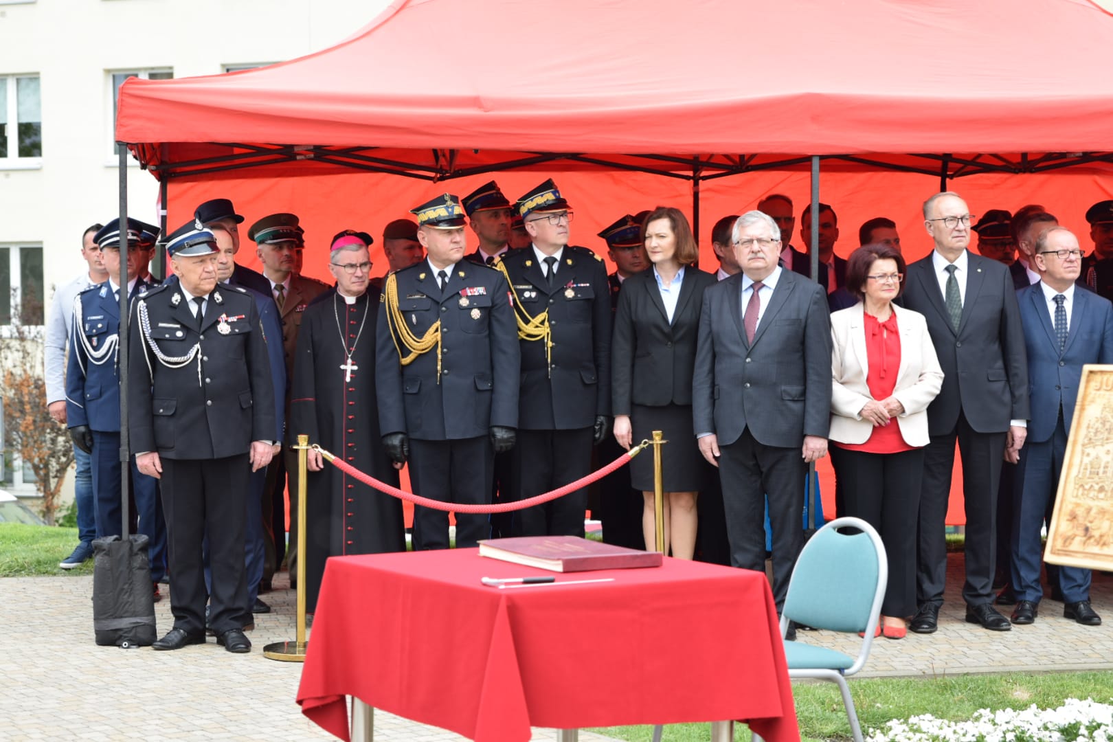 Zastępca komendanta głównego, podkarpacki komendant wojewódzki w otoczeniu zaproszonych gości stoją na uroczystości pod namiotem koloru czerwonego