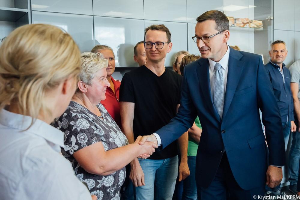 Premier Mateusz Morawiecki wita się z pracownicą firmy. 