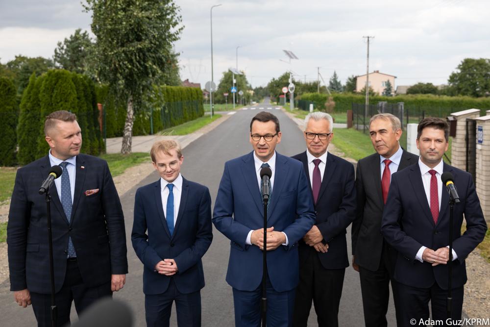 Premier oraz inni stoją podczas konferencji.