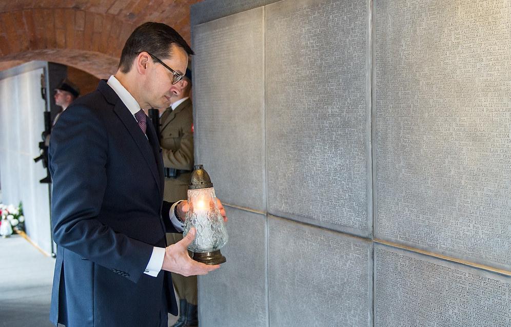 Premier Mateusz Morawiecki trzyma znicz w Muzeum Katyńskim.