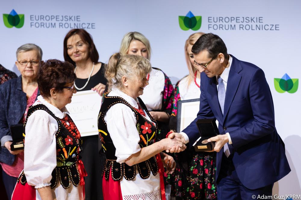 Premier Mateusz Morawiecki wręcza kobiecie w stroju ludowym nagrodę.