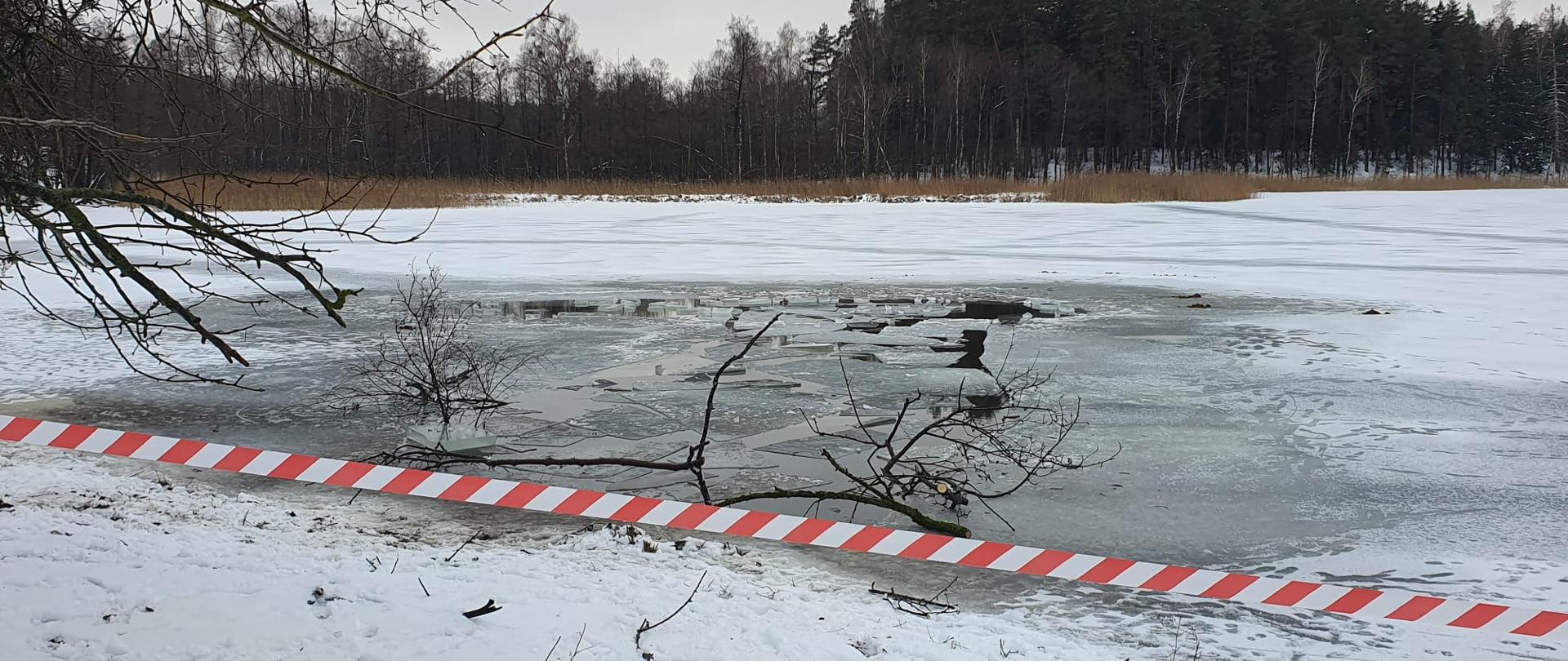 Jezioro zabezpieczone taśmą ostrzegawczą, na jeziorze załamane tafle lodu po akcji ratowniczej