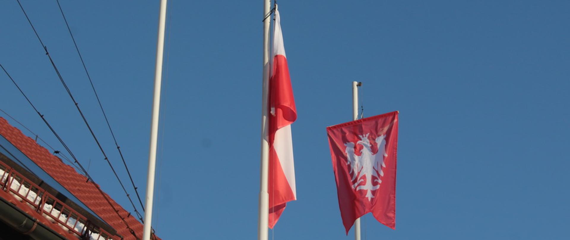 Flagi wywieszone przed Komendą PSP w Pleszewie z okazji Narodowego Dnia Zwycięskiego Powstania Wielkopolskiego - zbliżenie na flagi