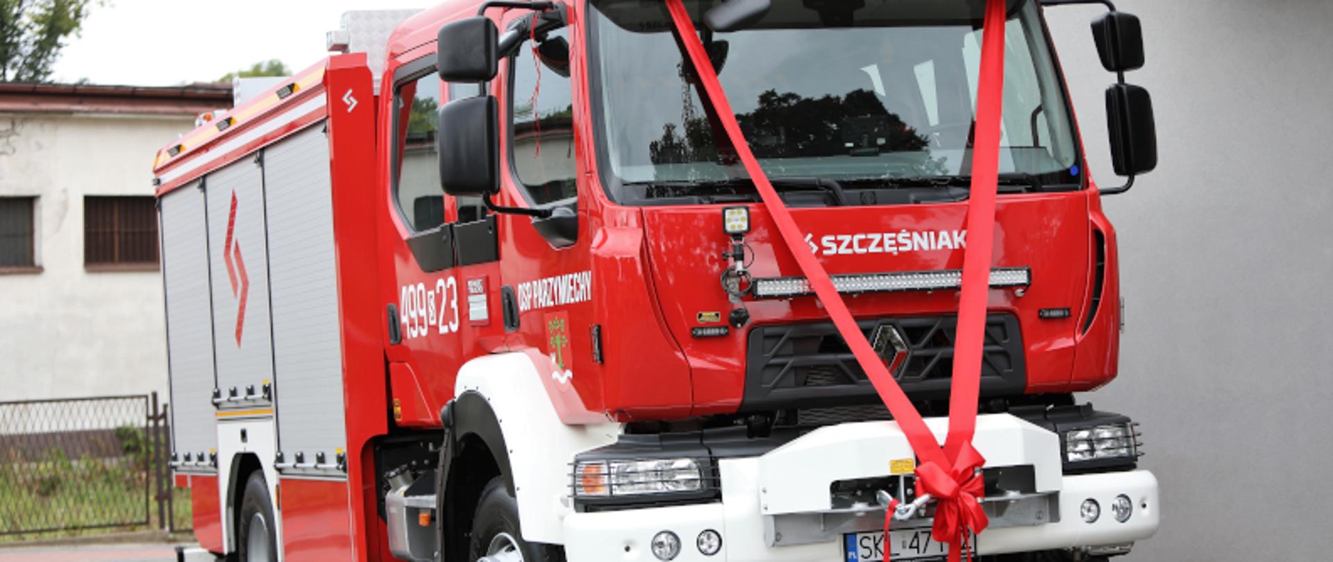 Samochód ratowniczo-gaśniczy przewiązany czerwoną wstążką, przekazywany jednostce OSP