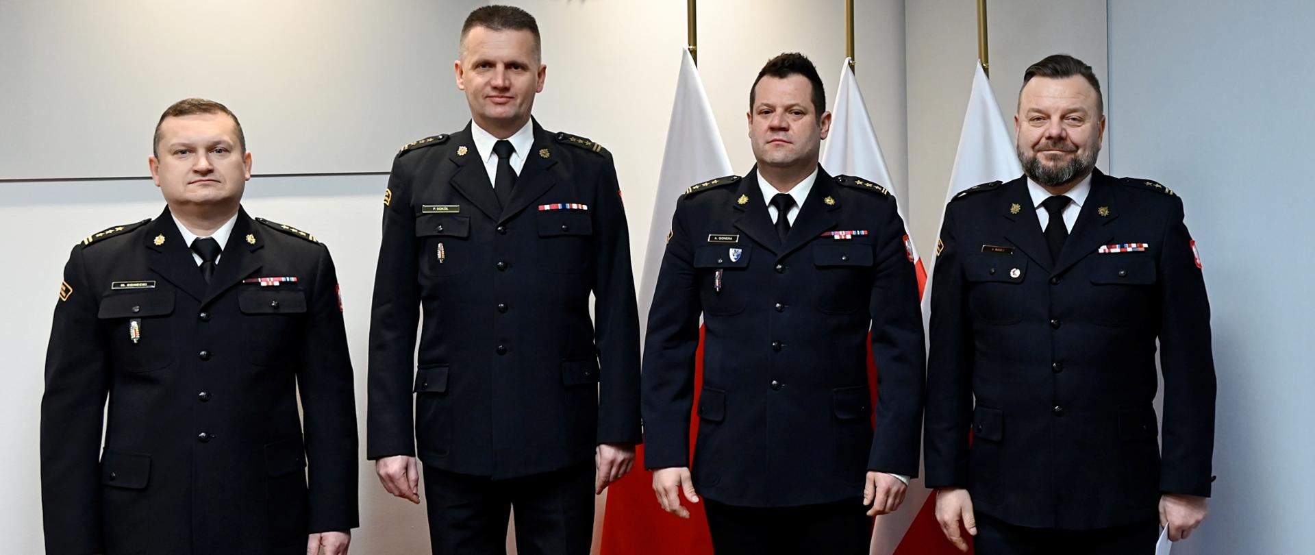 st. bryg. Artur Gonera MKW PSP, bryg. Paweł Sokół Komendant Powiatowy w Szydłowcu, bryg. Arkadiusz Madej p.o. Zastępcy Komendanta Powiatowego PSP w Szydłowcu oraz st. bryg. Marcin Konecki Naczelnik Wydziału Kadr KW PSP pozują do wspólnego zdjęcia