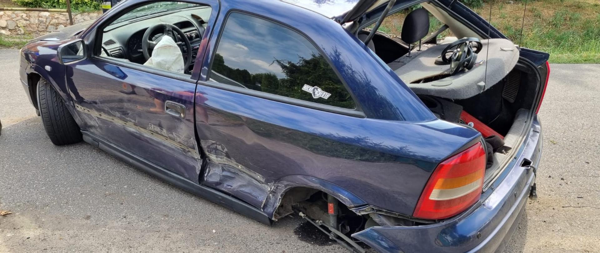 Widać uszkodzony lewy bok i tył pojazdu, przy samochodzie brak tylnego koła