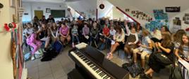 Siedząca grupa dzieci, wchodząca w skład chóru, która bierze udział w warsztatach chóralnych w ramach VII Międzynarodowego Festiwalu Muzyki Kameralnej