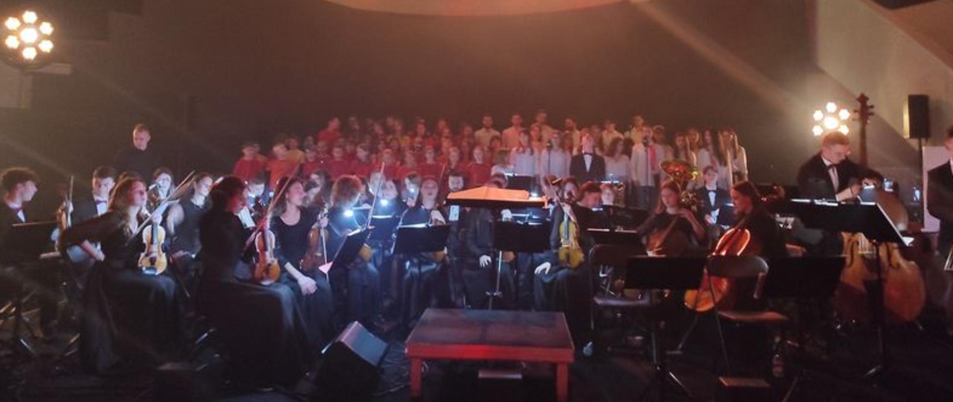 zdjęcie przedstawia Orkiestrę Symfoniczną PSM w Mielcu na otwarciu Podkarpackiego Centrum Nauki "Łukasiewicz" w Jasionce z kulą ziemską zawieszoną nad głowami muzyków