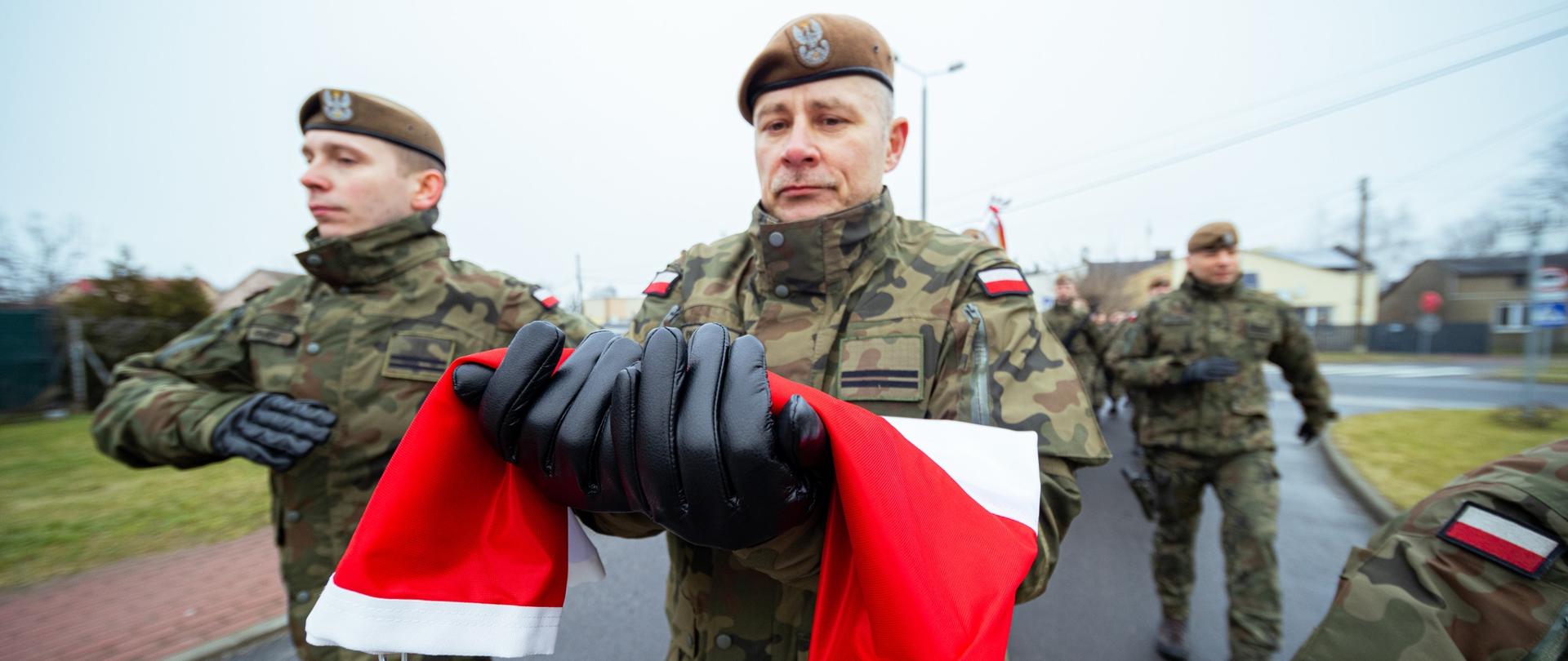Żołnierz niosący flagę RP