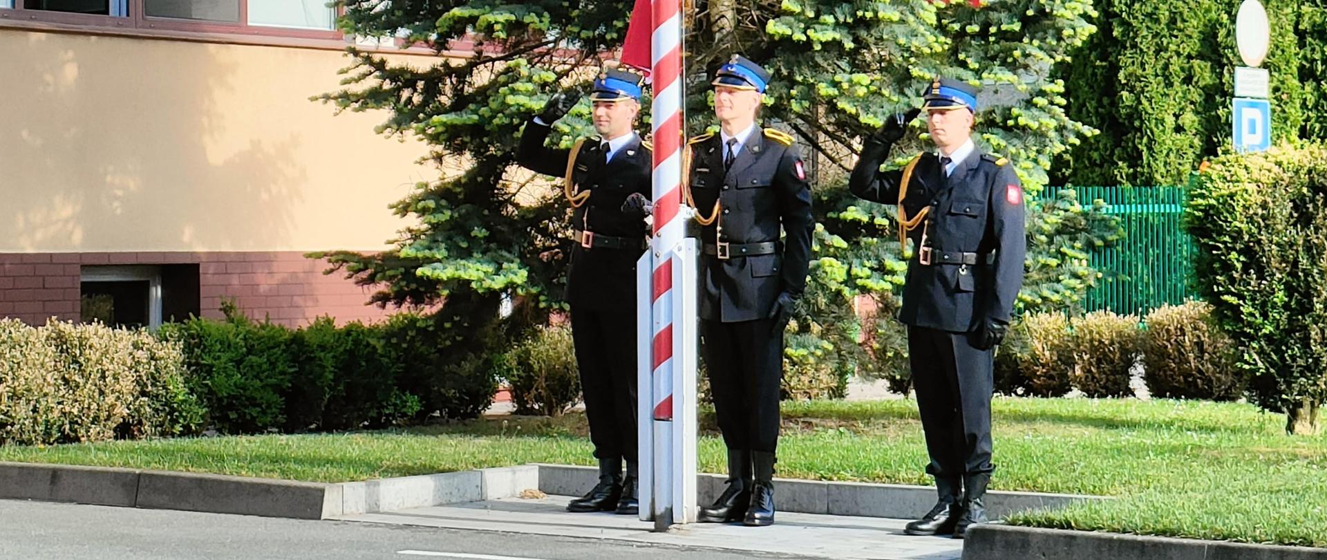 Strażacy podczas wciągania flagi państwowej na maszt