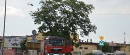 Wspólna akcja strażaków i LPR. Parking jednego z rawickich hipermarketów. Wóz straży pożarnej b lokuje wjazd na parking. W tle budynki i drzewo. Nad koroną drzewa odlatujący śmigłowiec Lotniczego Pogotowia Ratunkowego. 