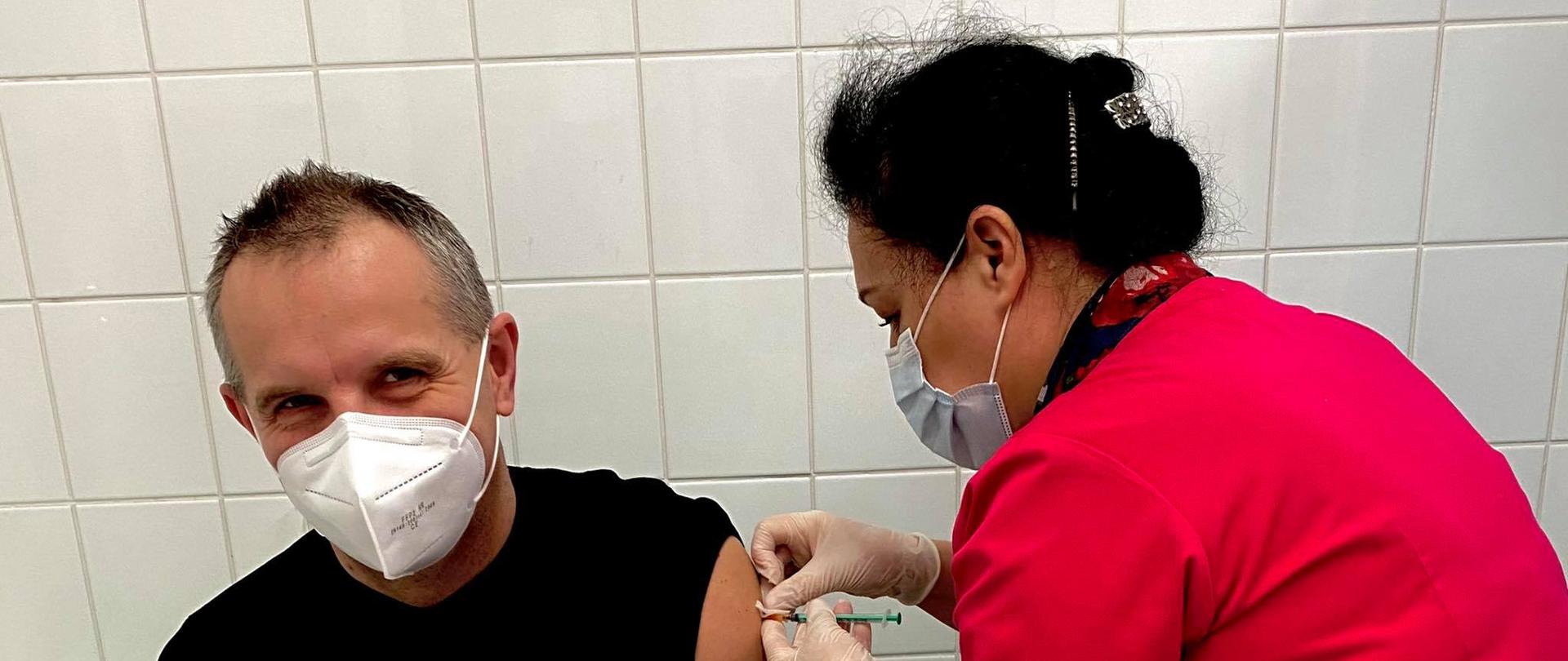 Widoczny funkcjonariusza psp i osoba dokonująca szczepienia przeciw COVID-19