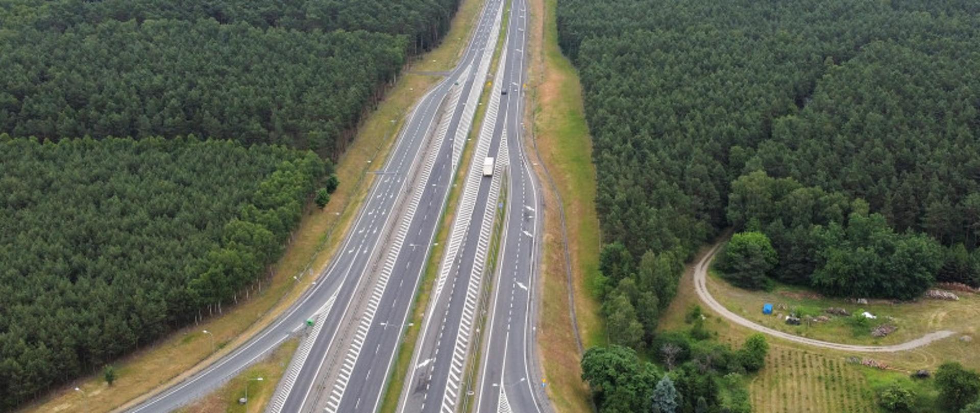 Na zdjęciu widoczna droga ekspresowa S10. Ujęcie z lotu ptaka. Widoczny węzeł drogowy z drogami rozjazdowymi. Drogę otacza gęsty las.
