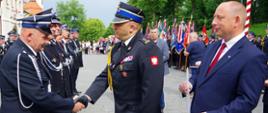 Widok z boku. Zastępca Komendanta Wojewódzkiego gratuluje odznaczonym druhom OSP. Obok Wojewoda Małopolski. 