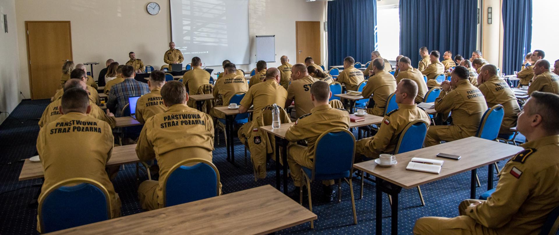 Funkcjonariusze PSP w ubraniach służbowych i sztabowych oraz pracownicy cywilni KW PSP siedzą na sali konferencyjnej podczas narady służbowo - szkoleniowej, która odbywała się dla pionu operacyjno-szkoleniowego PSP województwa opolskiego. 