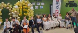 Grupa uczniów prezentuje przygotowany układ artystyczny podczas jubileuszowych obchodów 15-lecia Krytej Pływalni w Kłodzku. Młodzi wykonawcy występują na terenie obiektu, pokazując efekty swoich przygotowań i wspólnie uczestnicząc w uroczystym wydarzeniu.