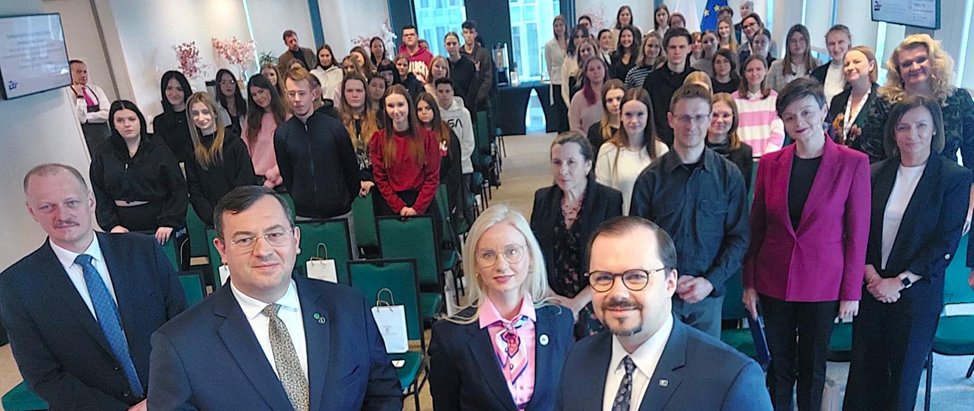 Grupa osób stojąca na sali wykładowej podczas Seminarium.