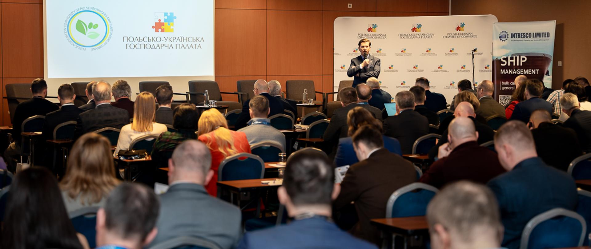 sekretarz stanu Rafał Romanowski stojący przed zebranymi z mikrofonem w dłoni