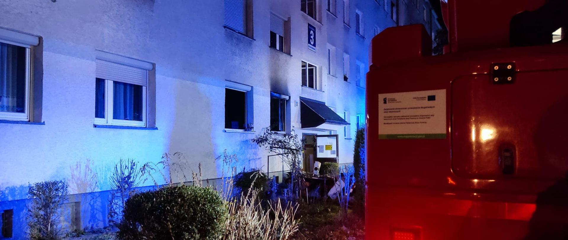 Na zdjęciu znajduje się blok mieszkalny oraz fragment podnośnika strażackiego