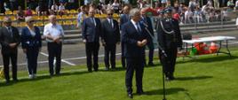 XI Powiatowe Zawody Sportowo-Pożarnicze OSP i MDP. Stadion w Miejskiej Górce. Na tle gości, komisji sędziowskiej i trybun, na których zasiadają kibice, do zebranych przemawia burmistrz Miejskiej Górki. 