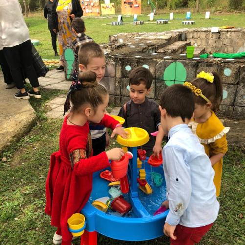 Grupa dzieci stoi wokół zabawki-młyna i bawi się różnymi elementami