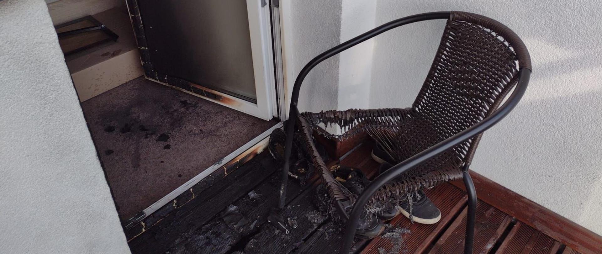 Dzień, na pierwszym planie spalony fotel wypleciony z technorattanu oraz spalona podłoga na balkonie.