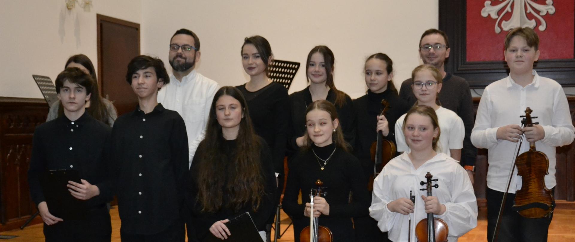 uczniowie klasy VB cyklu 6-letniego wraz z opiekunami podczas koncertu klasowego na scenie w sali królewskiej PSM Mielec