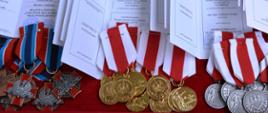 Ułożone na czerwonym suknie tacy medale i odznaczenia strażackie w oczekiwaniu na wręczenie.