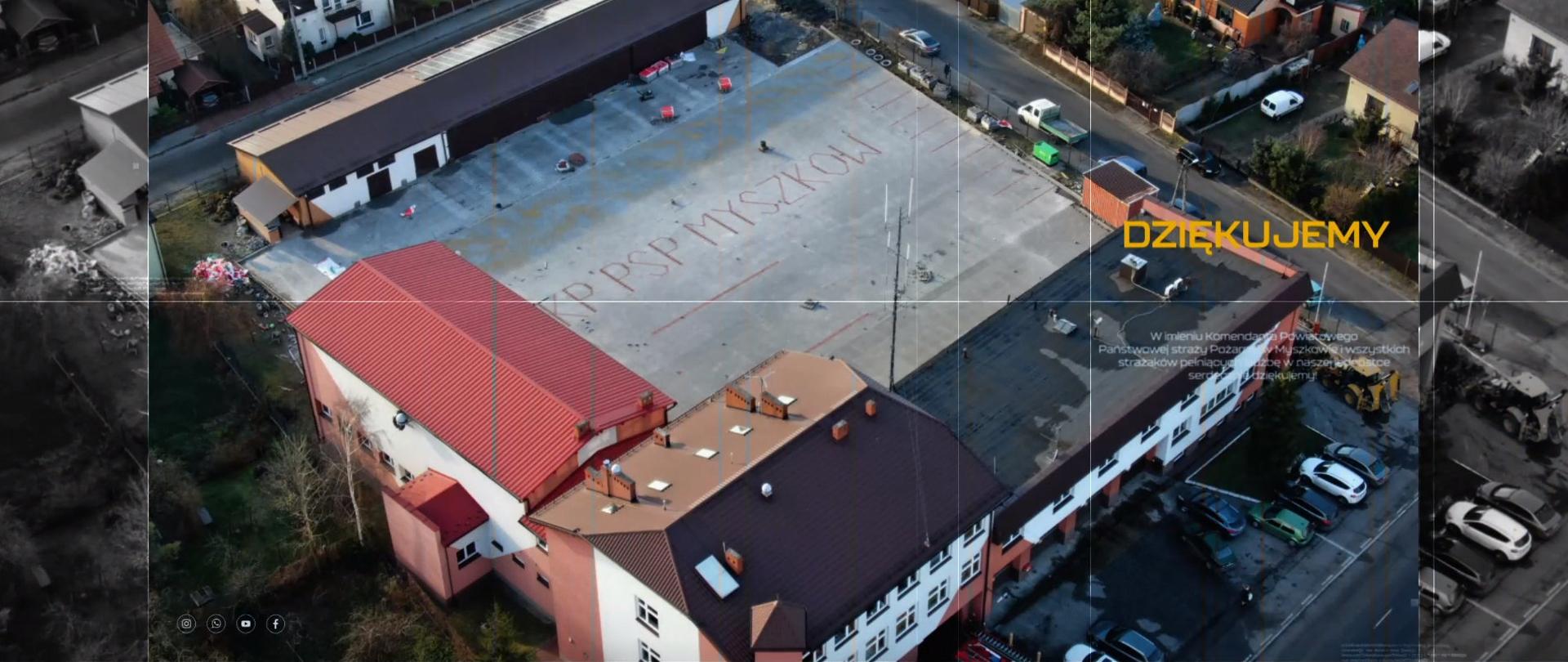 Zdjęcie przedstawia plac wewnętrzny Komendy Powiatowej PSP w Myszkowie - widok z góry. W centralnej części kadru znajduje się nowa nawierzchnia wykonana z kostki brukowej, otoczona przez budynki komendy. 