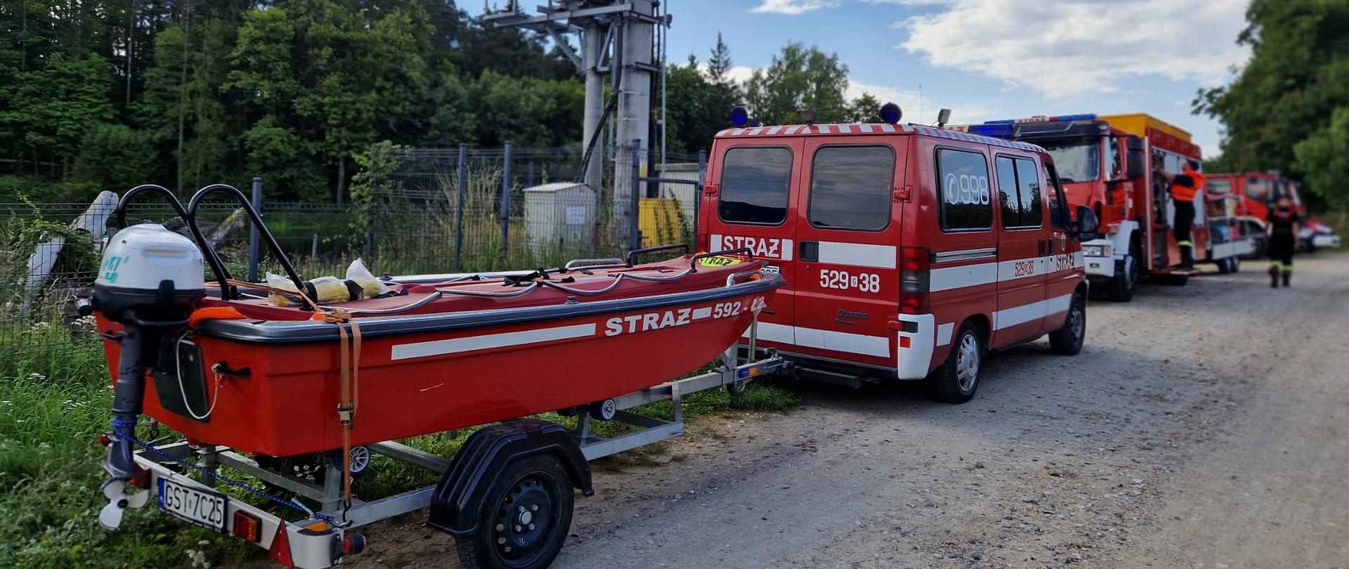 Zdjęcie przedstawia ustawione wzdłuż drogi pojazdy ratownicze straży pożarnej, w tle las.