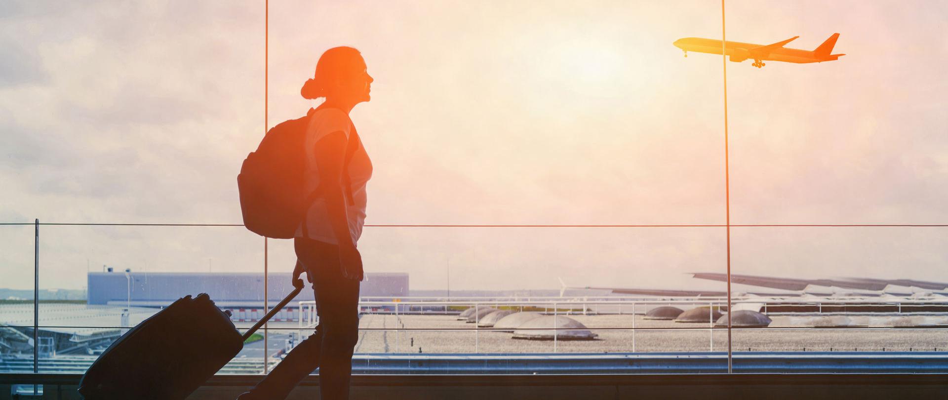 Turystka z walizką i plecakiem na lotnisku.