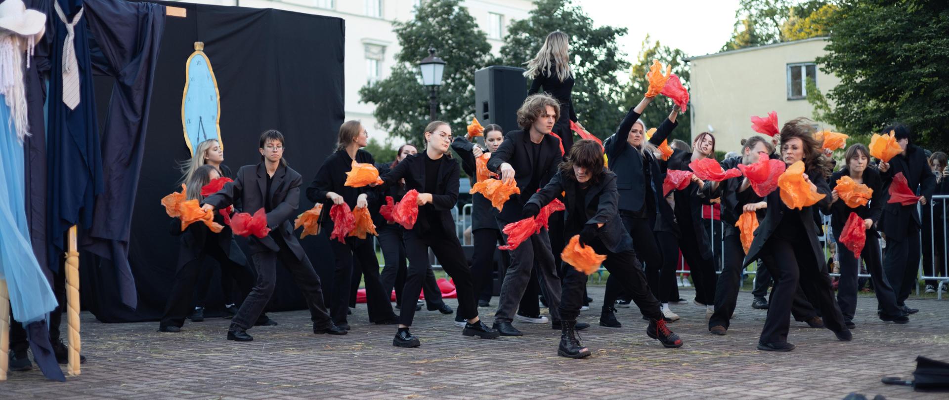 Grupa słuchaczy Studium Animatorów Kultury w Kaliszu ubrana w czarnych strojach występuje podczas Międzynarodowego Festiwalu Artystycznych Działań Ulicznych La Strada XXXI Edycja w Kaliszu, organizator Centrum Kultury i Sztuki w Kaliszu