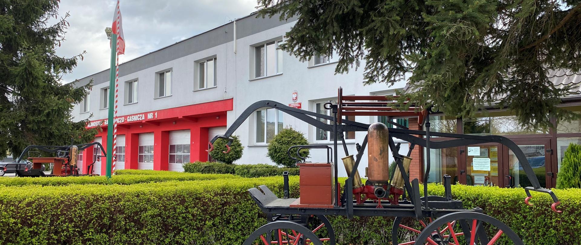 Na zdjęciu obiektu Komendy Miejskiej PSP we Włocławku. Na pierwszym planie stara sikawka - element dekoracyjny przed budynkiem. W tle widoczne bramy garażowe.