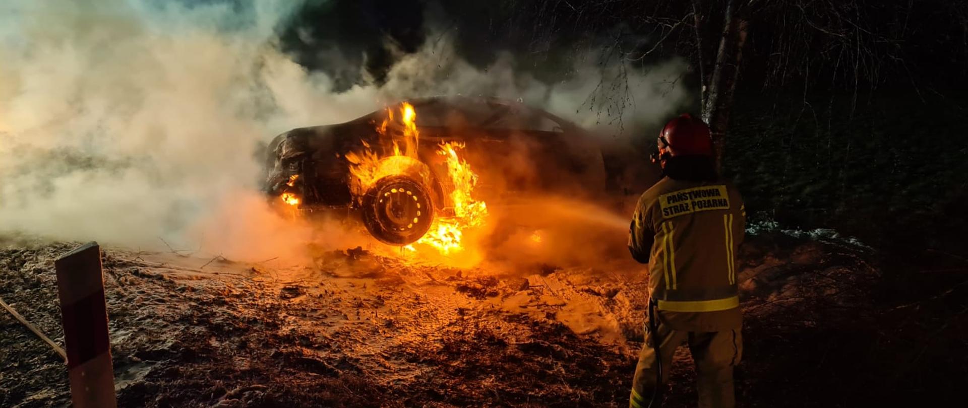 Strażak gasi samochód. Pojazd w ogniu.